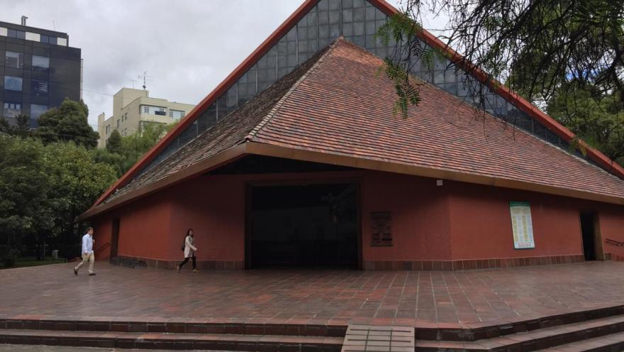  Parroquia Inmaculada Concepción de frente fachada de forma triangular con personas caminando cerca.