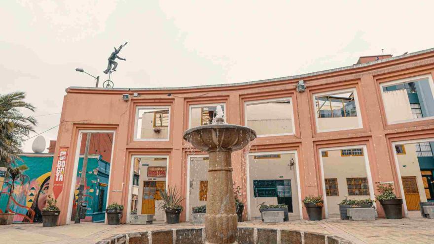 Plazoleta del Chorro de Quevedo en primer plano la pila de agua y la pared de fondo con la escultura de un payaso en monociclo.