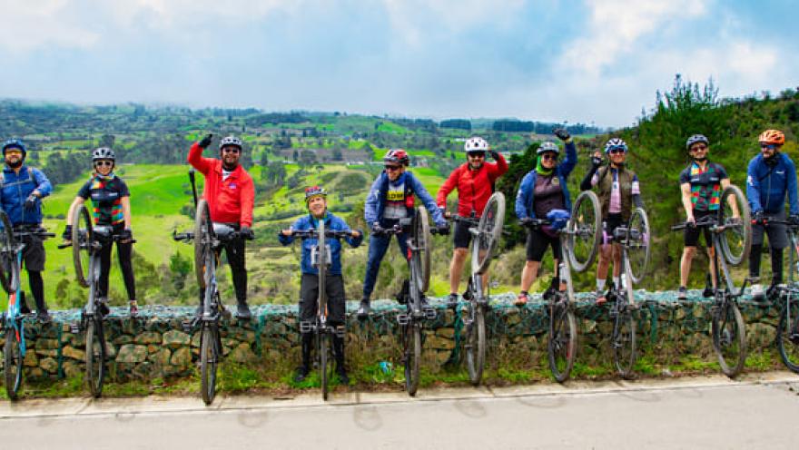 Grupo de ciclistas celebran con un paisaje de montañas de fondo.