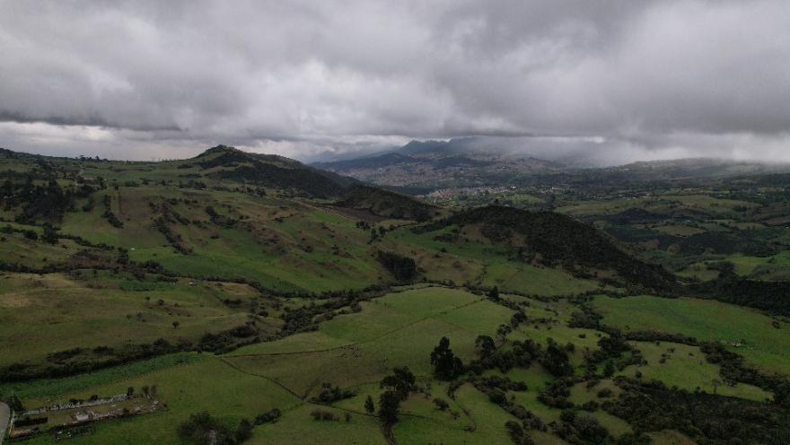 Paisaje de montañas verdes con cielo gris oscuro sin construcciones alrededor.