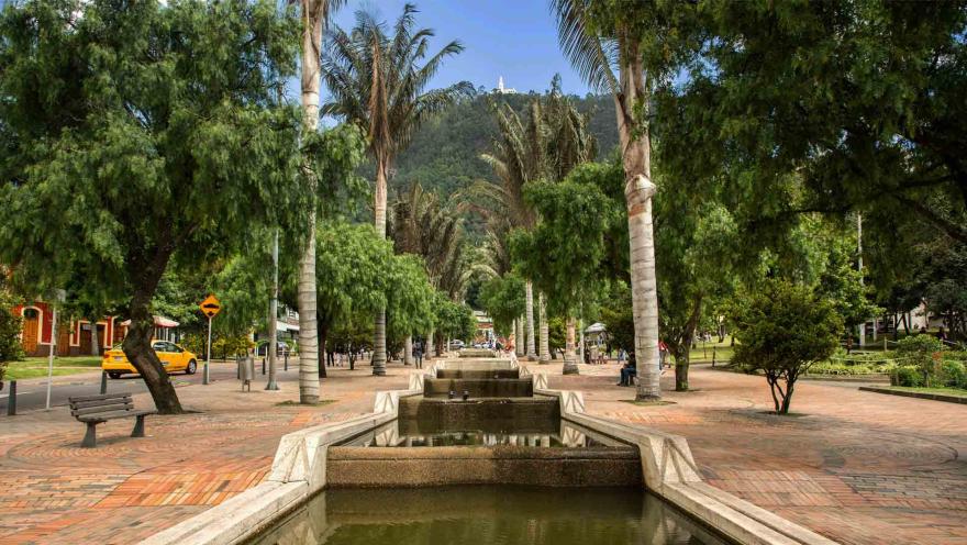 Eje ambiental con caudal de día con árboles y palmas a los lados. Al fondo se ve el cerro de Monserrate