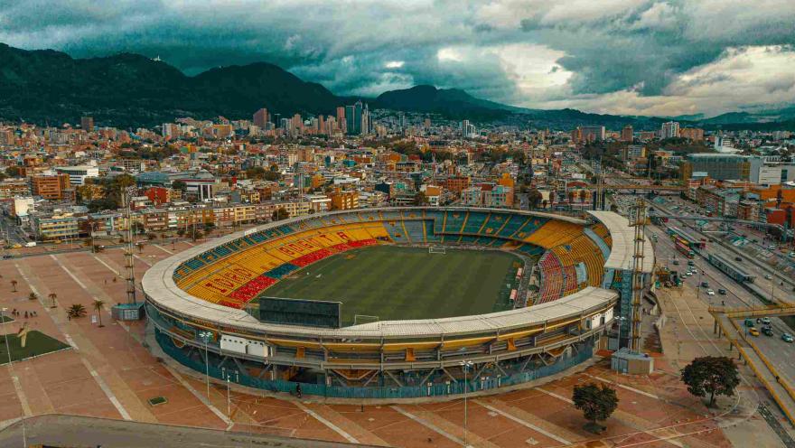 Estadio El Campín plano general visto de norte a sur con la ciudad de fondo. El cielo es gris.