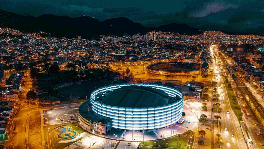 Panorámica nocturna vista desde arriba del Movistar Arena y del Estadio El Campín, de noche y con la ciudad iluminada de fondo. 