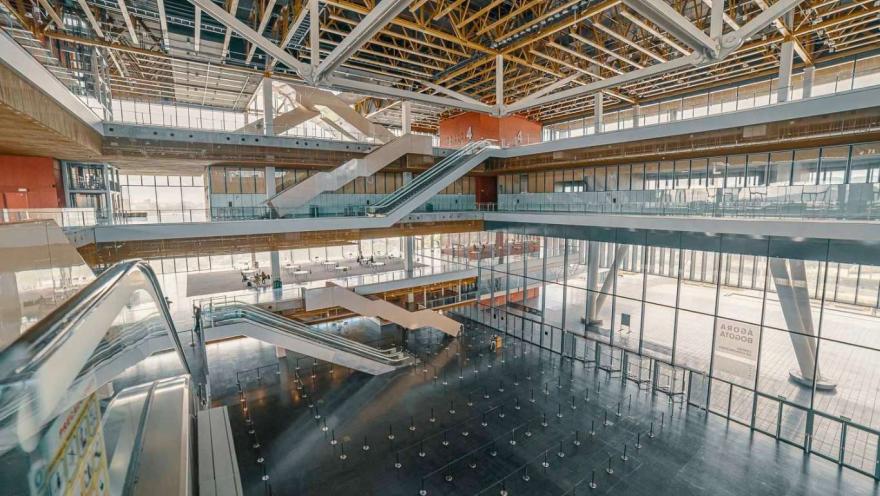 Interior de un gran salón en el que hay varios pisos y conexiones con escaleras eléctricas. El lugar tiene grandes ventanales que dan a la calle donde hay luz de día.