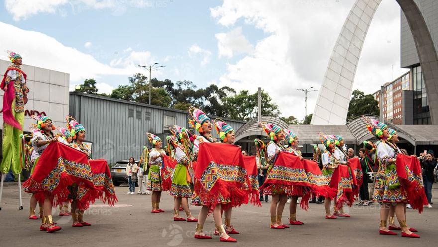 Grupo de mujeres bailarinas con ropas de alguna cultura indígena colombiana.  llevan faldas coloridas y sombreror de colores en fique.