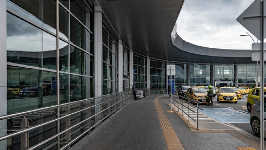 Exterior of a building with many windows. Several taxis are parked in front.