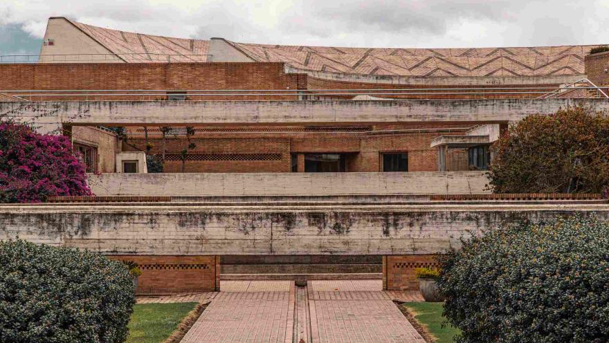 Estructura cuyas paredes y piso es de ladrillo y concreto. Hay varias flores y plantas a los lados.