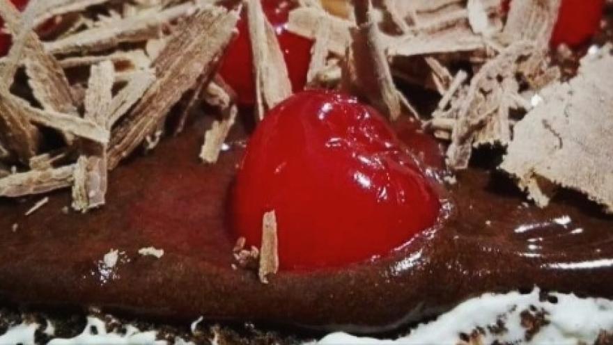 A slice of chocolate cake with cherries.