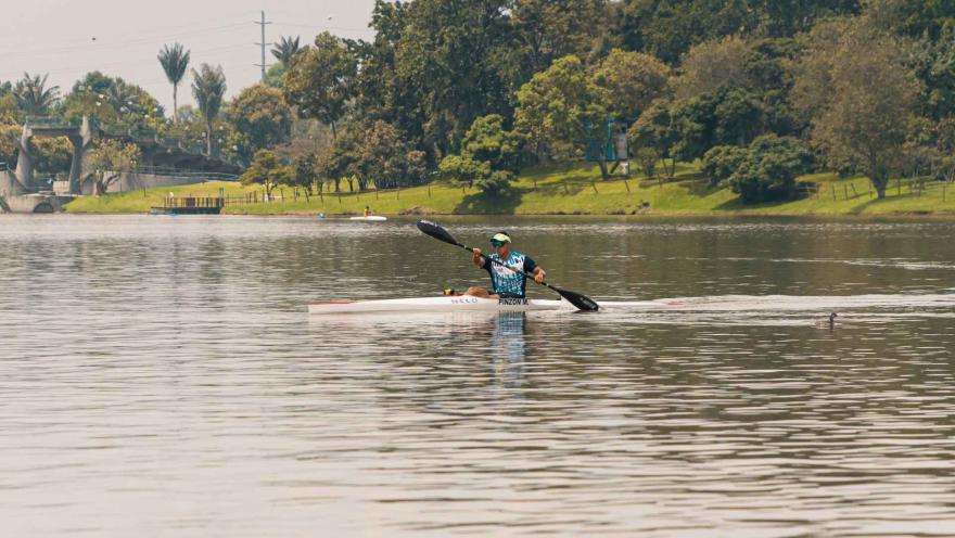Parque Simón Bolívar con un deportista nautico en kayak navegando por el lago. El hombre con ropa depoertiva mueve su remo.