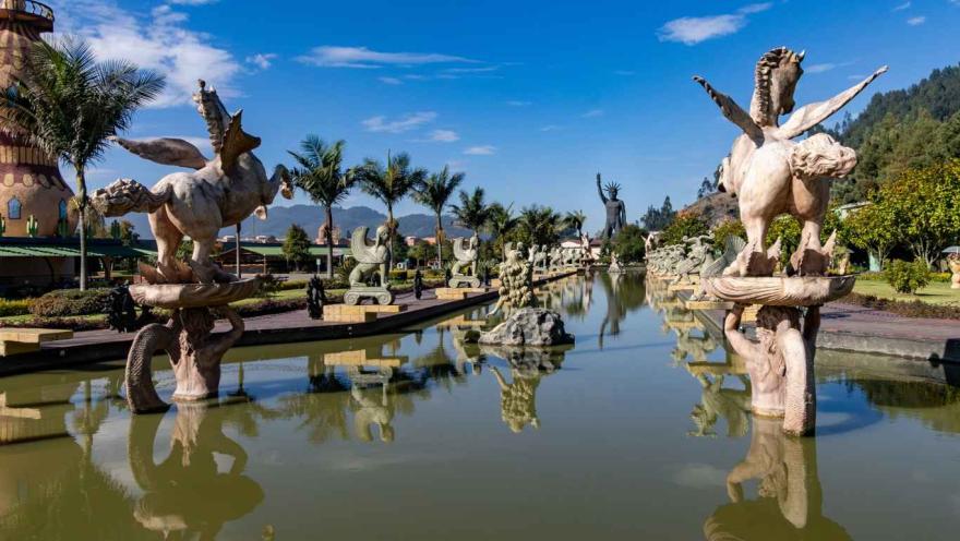 Un lago rodeado por estatuas de figuras mitológicas como minotauros y una medusa gigante.