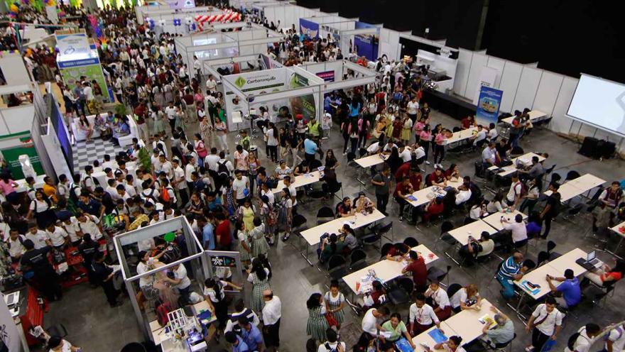 Salón con varios stands abarrotados de personas y visto desde arriba.