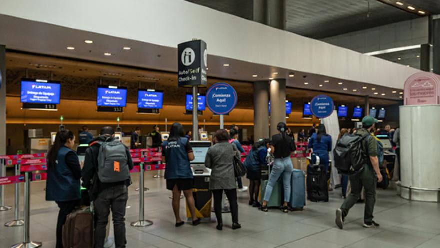Interior of an airport showing some people walking with suitcases.