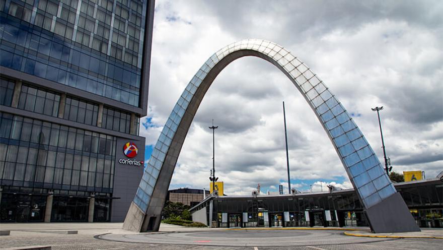 Entrada principal de Corferias con su óvalo gigante en metal y concreto. Al lado un edificio alto con el logo de Corferias.