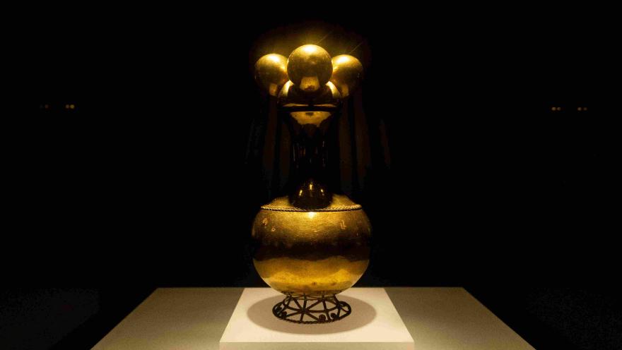 Pieza de Poporo dorado. Una luz desde arriba la ilumina.