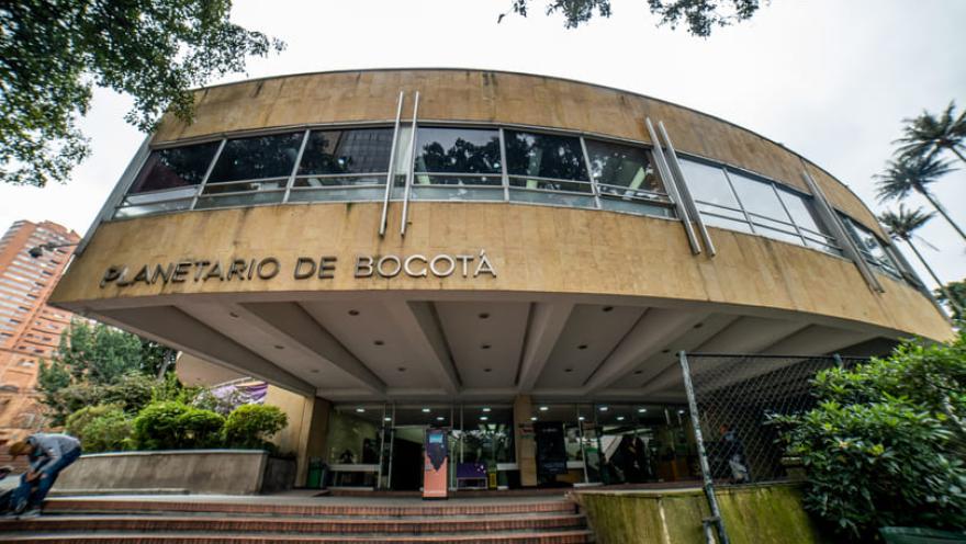  Fachada en placa amarilla con ventanas en la que resalta el título de "Planetario de Bogotá".