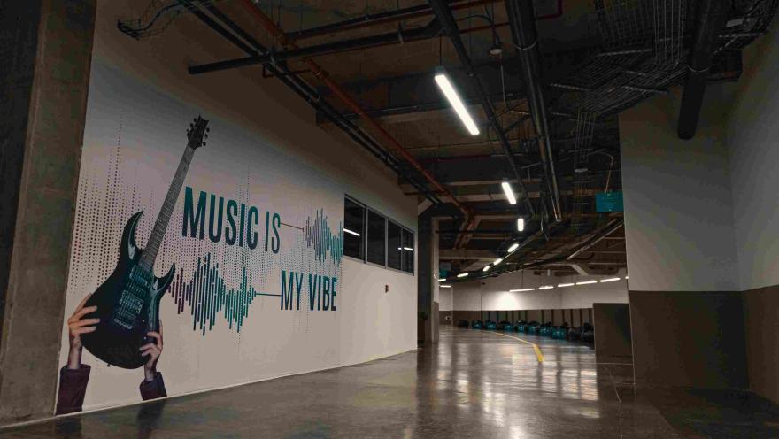 Al interior pared blanca con un afiche de letras en azul que dice "Music is my vibe"