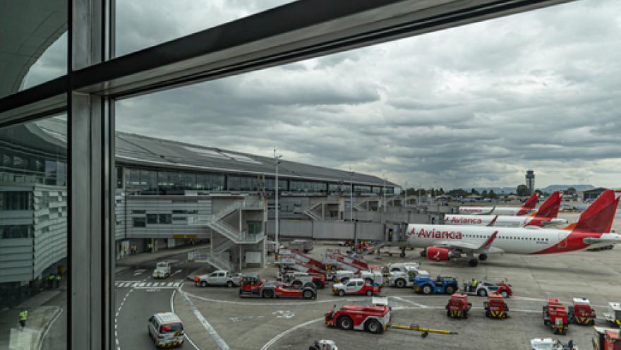 Interior window of an airport showing some Avianca airplanes parked on the ground.