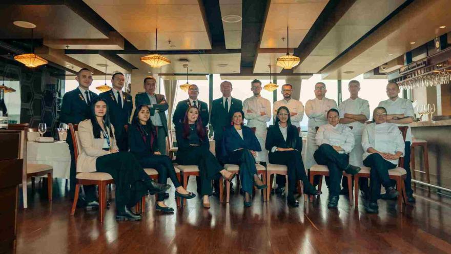 Un grupo diverso de personal de restaurante, incluyendo chefs y gerentes, posa elegantemente en el comedor.