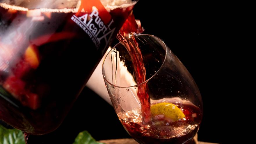 Se sirve sangría roja con frutas en una copa de vino, mostrando la frescura y el color de la bebida.