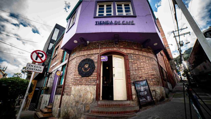 Fachada de edificación antigua de ladrillo y donde hay un aviso con una leyenda que dice: "Tienda de café".