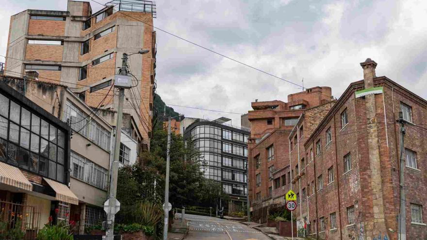 Calle residencial vista desde abajo rodeada de edificos en ladrillo al estilo de los años 70 y 80.