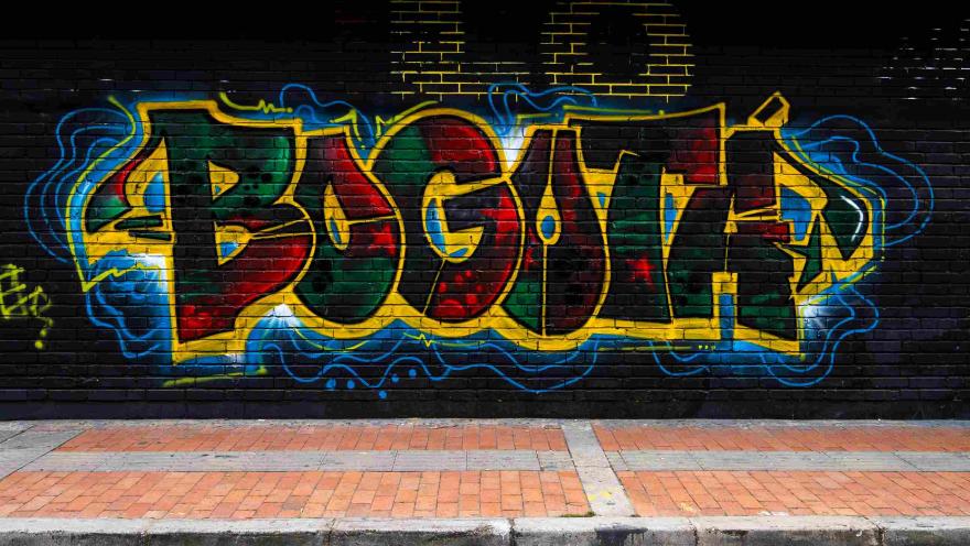 Pared de ladrillo negra pintada de colores rojo, azul y amarillo con la palabra "Bogotá"