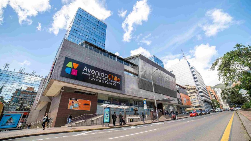 Fachada del Centro Comercial Avenida Chile, en baldosa gris y vidrio. Al frente hay una avenida sin carros. Hay detrás unos edificios altos en vidrio.