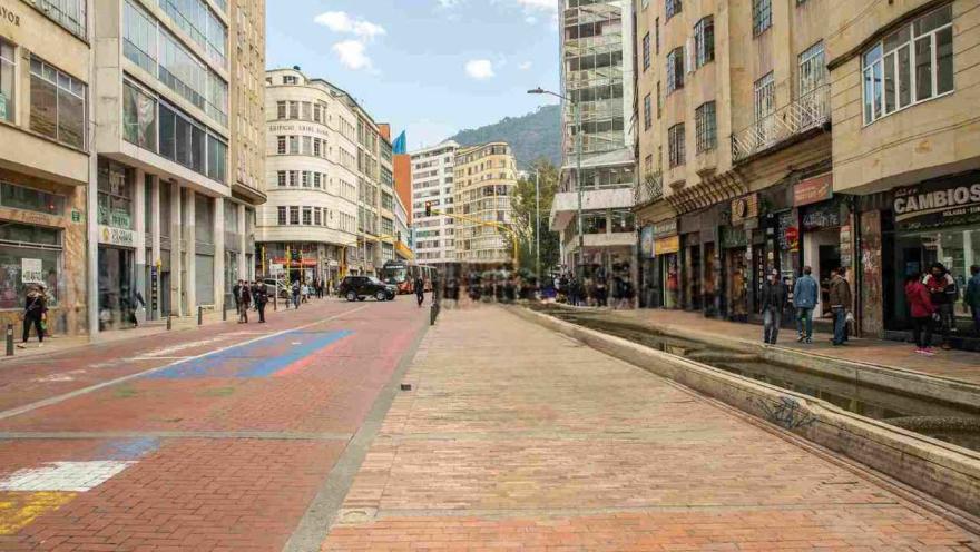 A promenade with a long fountain and several buildings with shops around it.