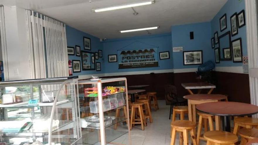 Interior de local comercial donde hay varias vitrinas, mesas y sillas.