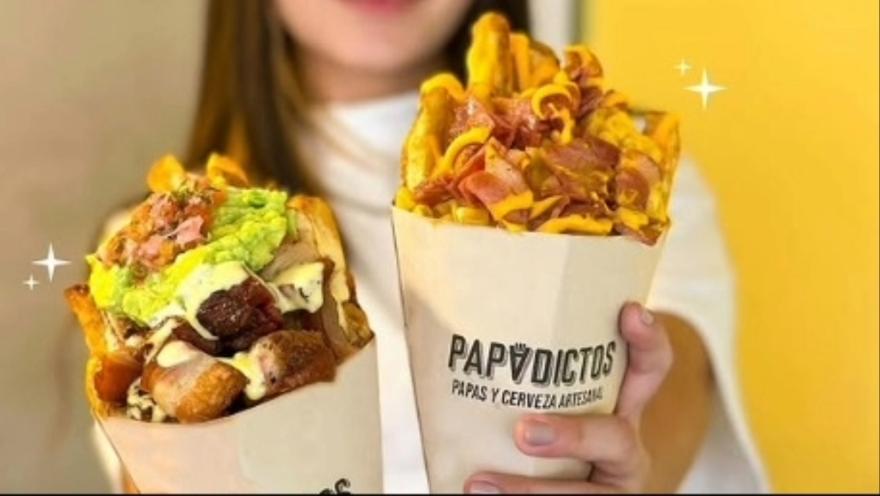 Primer plano de dos paquetes de papas a la francesa con salsas y otros trozos de comida rápida.