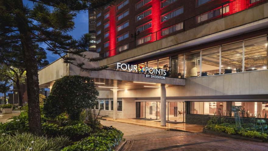 Exterior del hotel Four Points by Sheraton iluminado de noche, con entrada ajardinada.