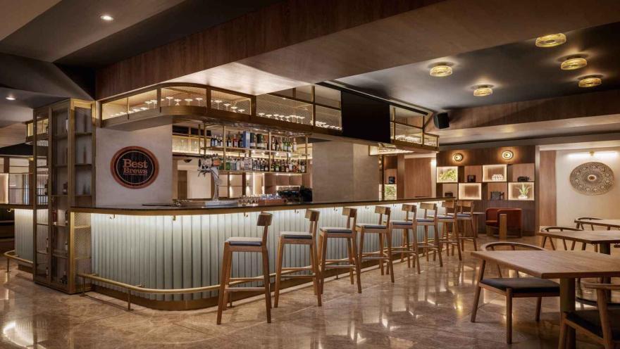  Bar moderno con taburetes, barra retroiluminada y estanterías de copas.