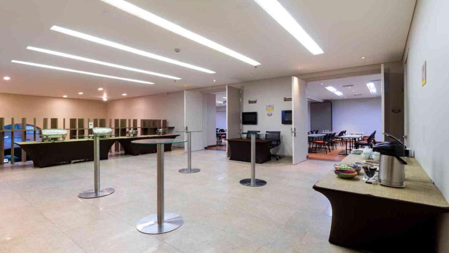  Un área de descanso y buffet con mesas altas y una estación de café, perfecta para pausas durante reuniones o eventos.