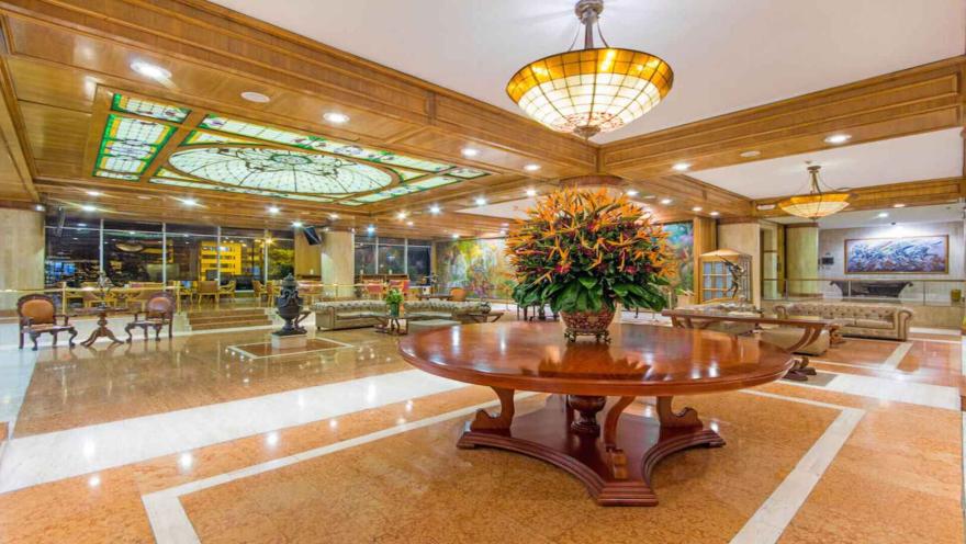  Lujoso lobby de hotel con una gran mesa central y vitrales. Impresionante entrada con decoración floral.
