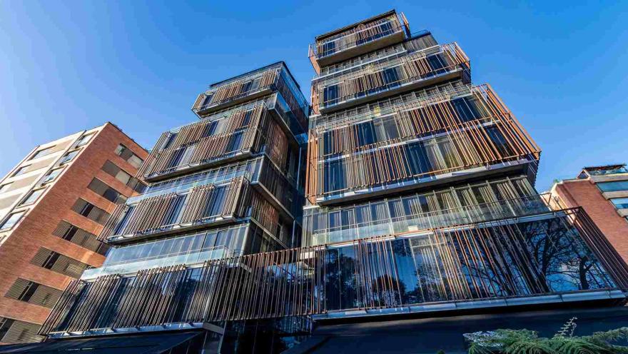 Un edificio moderno con una fachada distintiva de paneles verticales y grandes ventanales. La arquitectura es contemporánea y elegante.