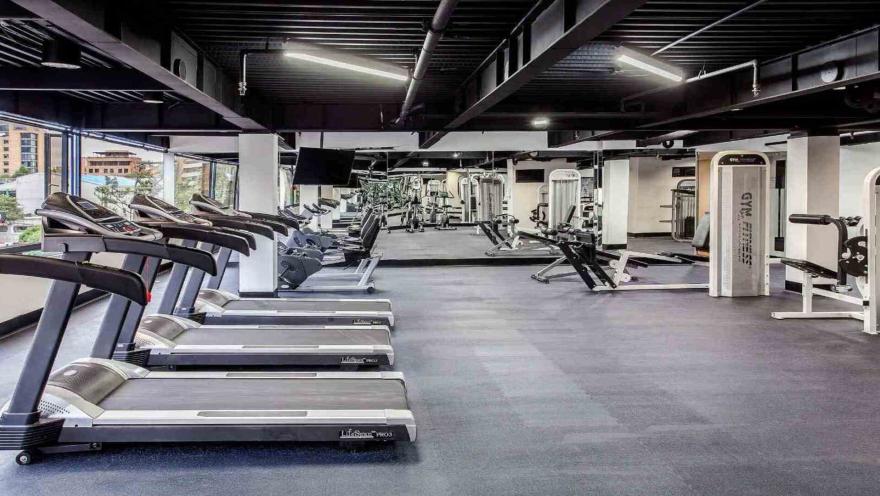 Un gimnasio de hotel amplio y bien equipado, con cintas de correr, máquinas de pesas y otros equipos de fitness, ideal para mantenerse activo.