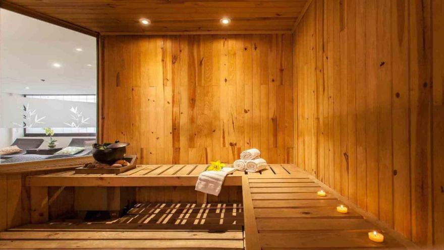 Una sauna de madera cálida y acogedora, con toallas apiladas y velas que añaden un toque de tranquilidad.