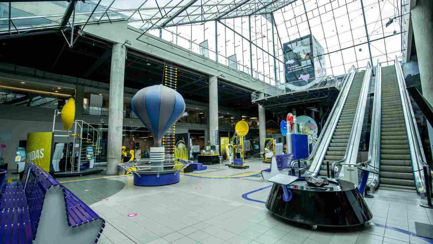Gran salón donde se observa un globo, unas escaleras eléctricas y un gran techo en vidrio.