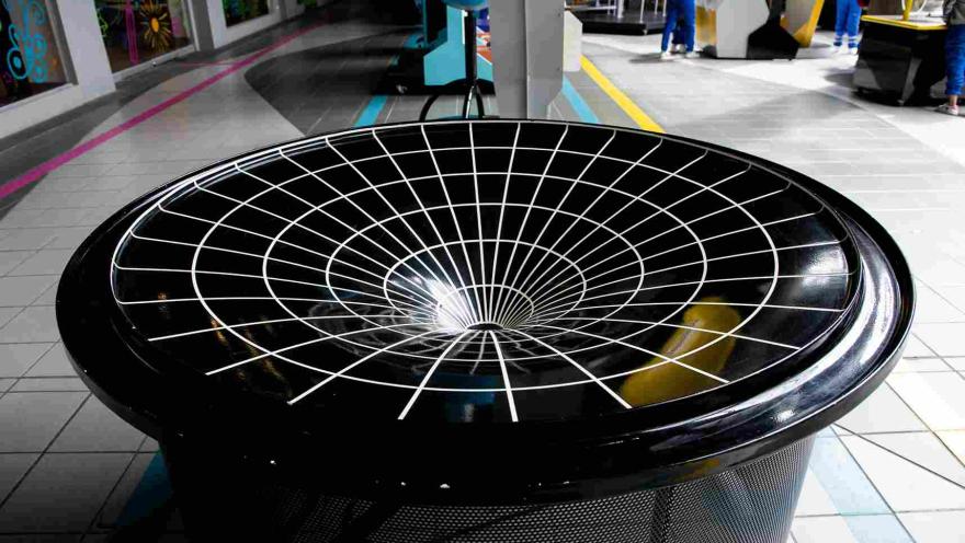 Figura geométrica compuesta por un embudo negro con rayas blancas que simula un hoyo negro.