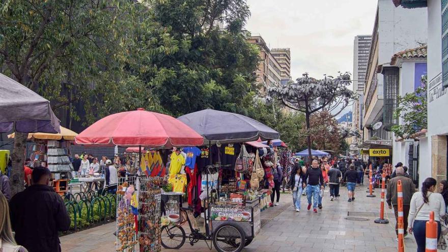 Panorámica de calle con locales de ventas ambulantes y personas que caminan alrededor.