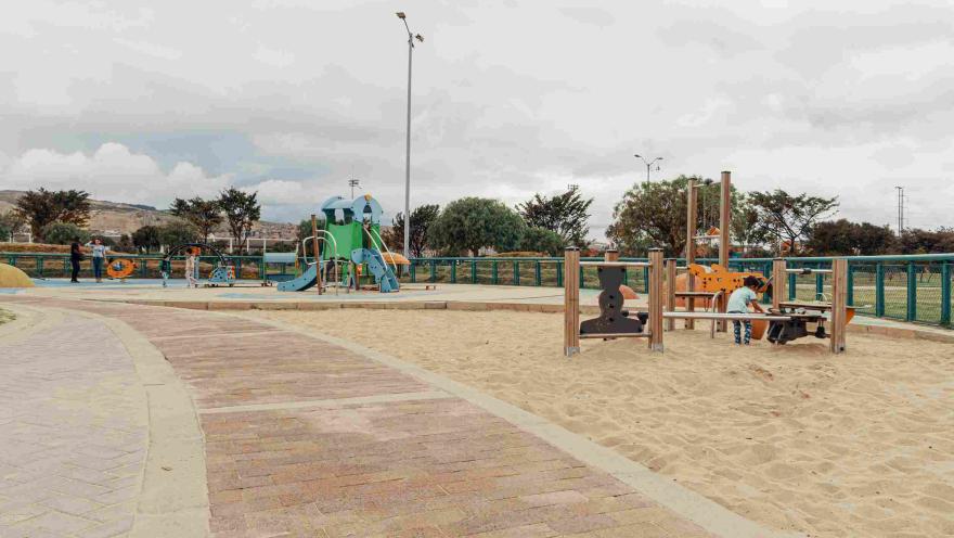 Parque infantil con arena en la que hay un niño jugando.