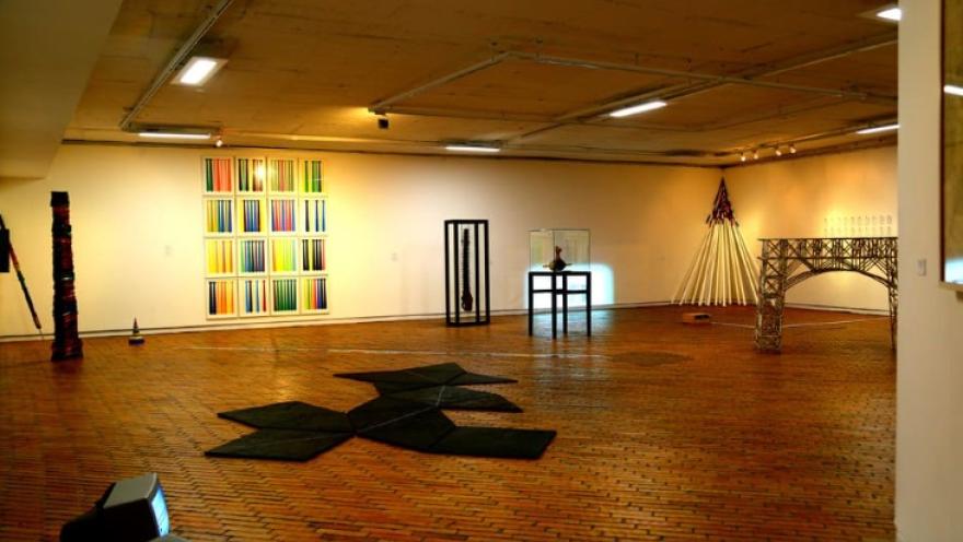  Sala interior con pintorescas obras de arte exhibidas en paredes y piso.
