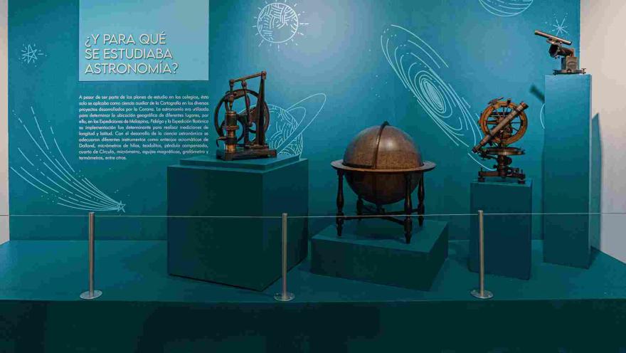 Cuatro objetos relacionados con astronomía: uno es un mapamundi redondo y en madera, y dos telescopios pequeños y metálicos. Hay un aviso con una leyenda que dice: “¿Y para qué se estudiaba astronomía?”.