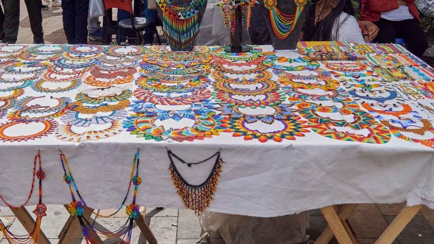 Una serie de collares de estilo artesanal con los colores de la bandera de Colombia, expuestos sobre una mesa.