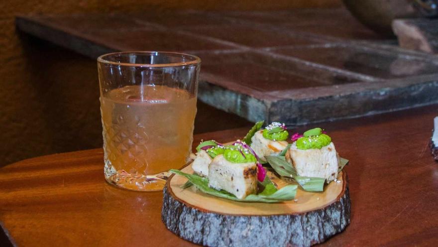 Exquisitos canapés en una tabla de madera rústica, acompañados de una bebida refrescante. 