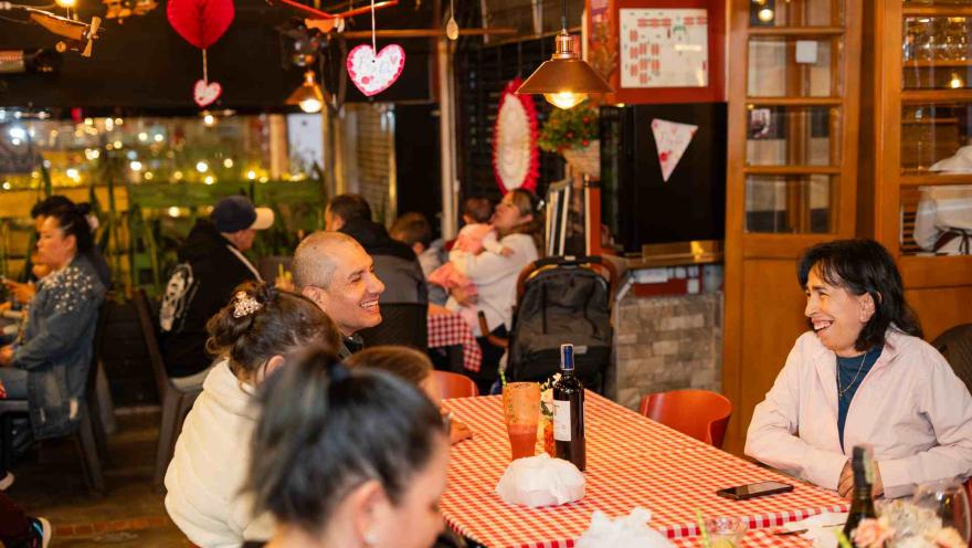 Clientes disfrutan de la cena y conversan animadamente en el ambiente concurrido del restaurante.