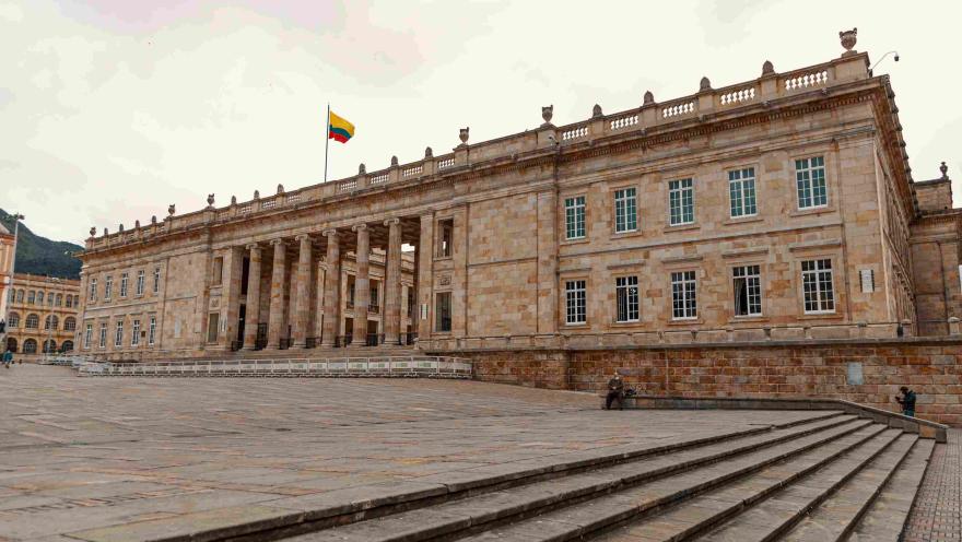 Fachada del Capitolio Nacional en piedra. Se observan algunas ventanas y la bandera de Colombia izada en lo alto.