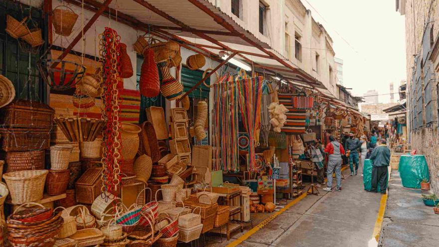 Panoramica de calle repleta de coloridos artículos artesanales como canastos y hamacas.