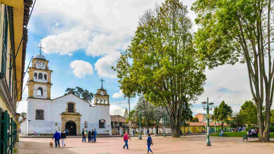 Plano general de la plaza de Fontibón en la que se observa la iglesia y una gran plazoleta al frente con personas y árboles.