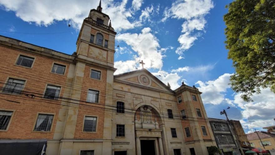 Fachada de la parroquia de San Alfonso en piedra y ladrillo. Arriba, el cielo es azul.